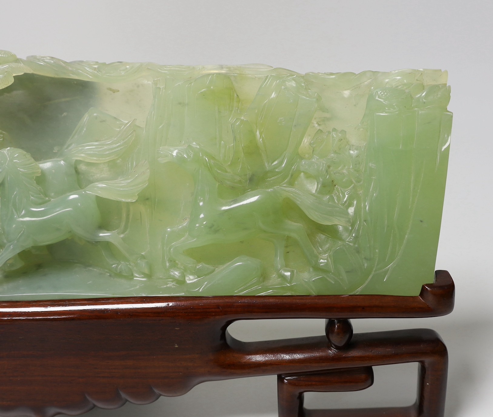 A large Chinese bowenite jade plaque of galloping horses, wood stand, 40cm wide